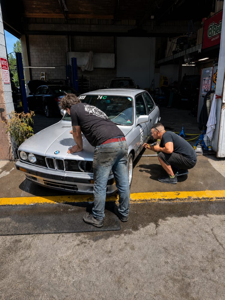 The River City Autohaus team working together on a BMW E30 track car outside the St. Helens shop
