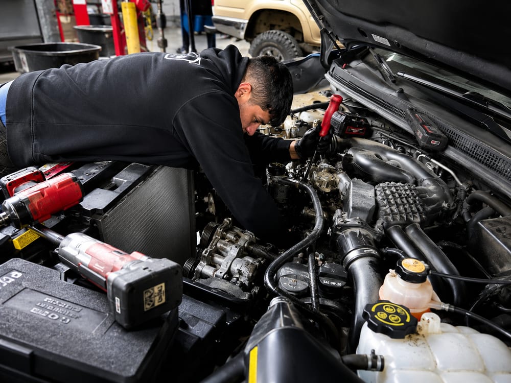 River City Autohaus technician diagnosing an engine, testing components under the hood