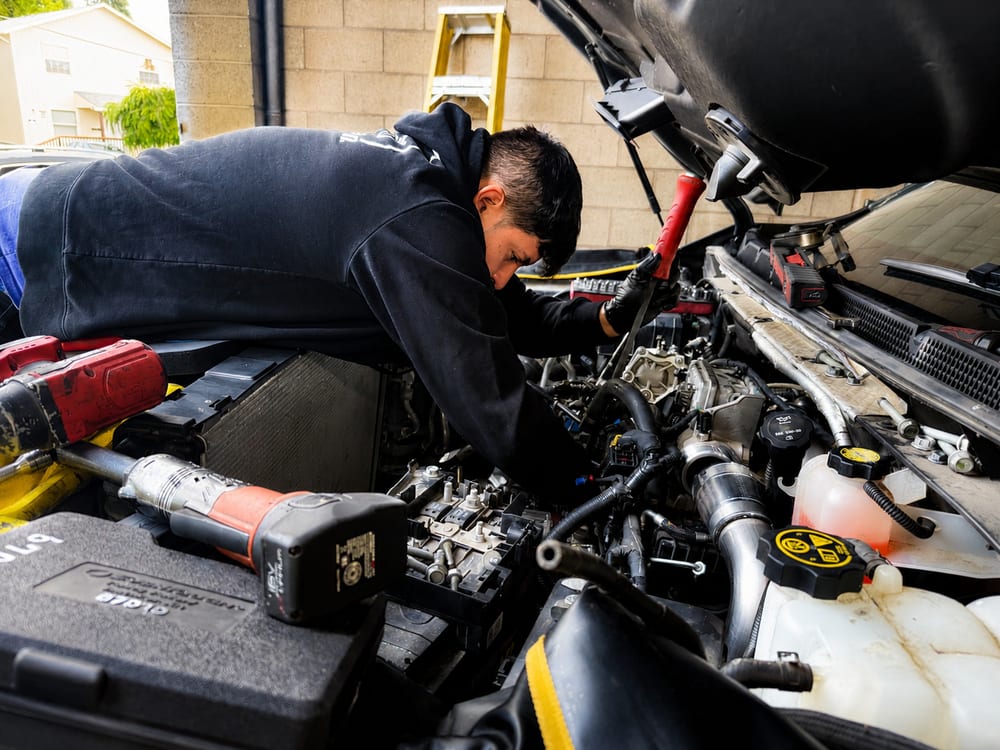 River City Autohaus technician working deep in a vehicle's engine bay during an engine repair